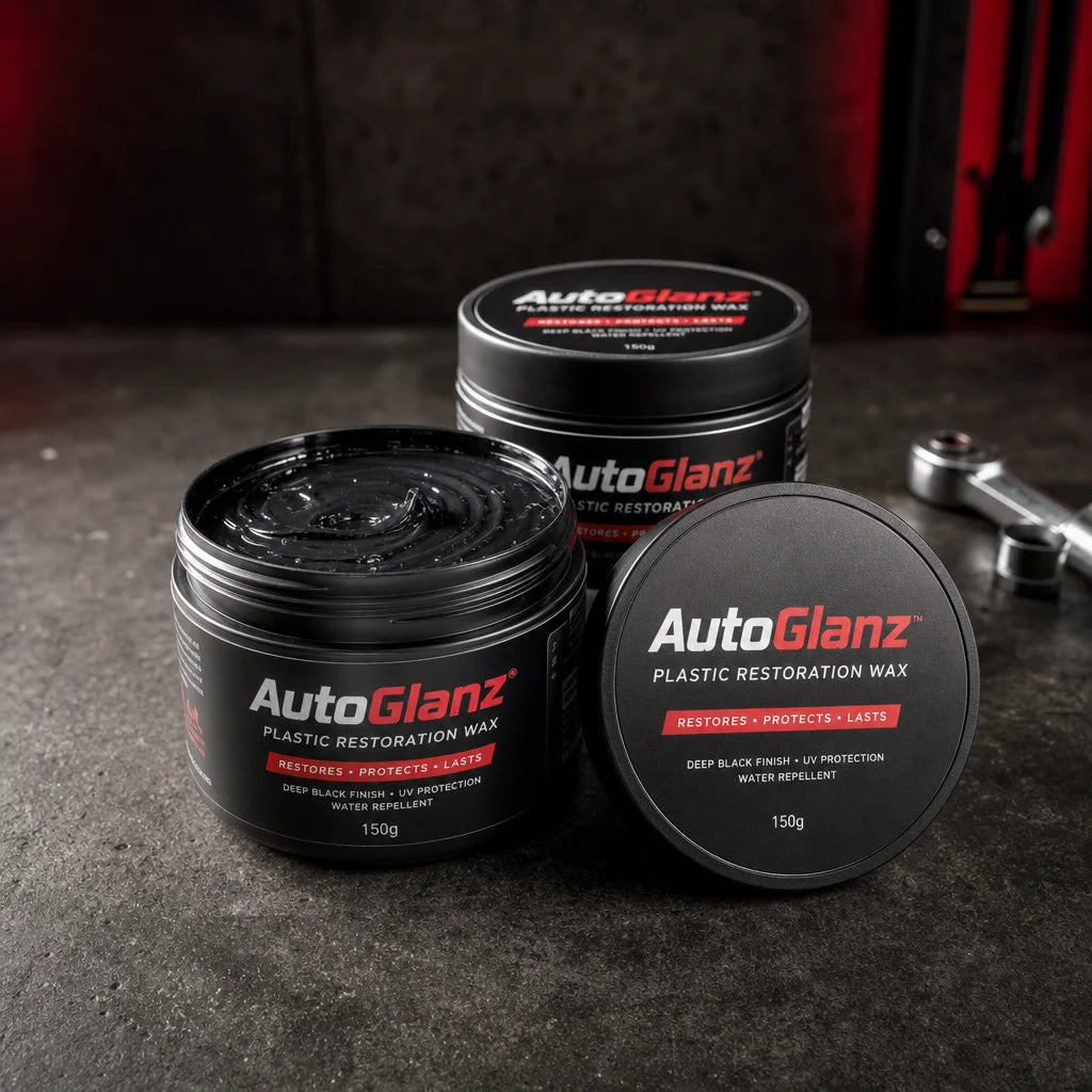 Three black jars of automotive plastic restoration wax arranged on a dark workshop surface. The jars